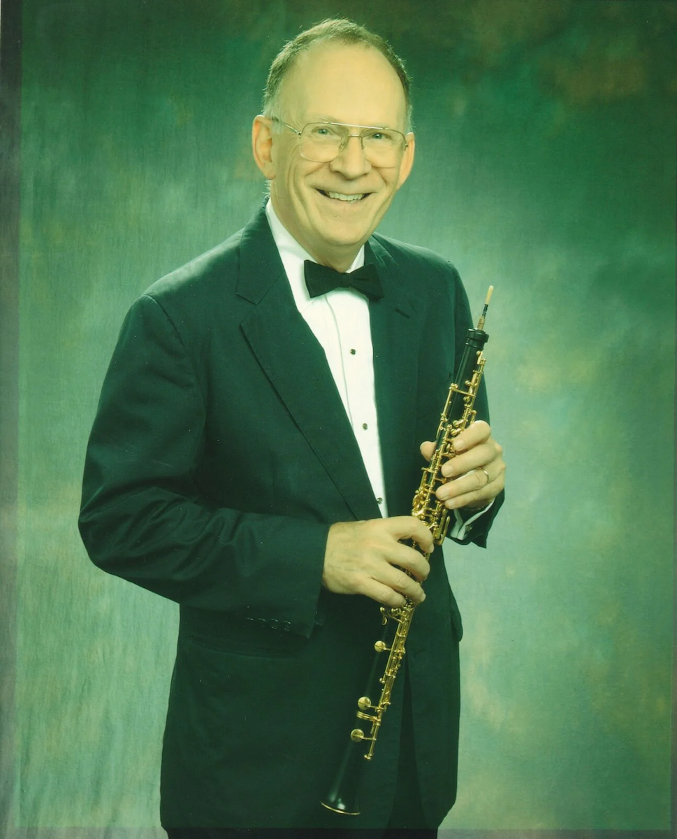 Donald John Schilling posing for a photo while holding an oboe