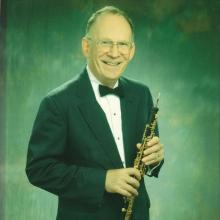 Donald John Schilling posing for a photo while holding an oboe.