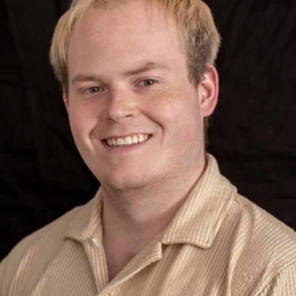 Lane Cargile, a white man with blonde hair smiling. He is wearing beige button up. 